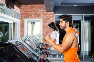 Hintli çekici çift fitness merkezinde ya da spor salonunda kardiyo eğitimi yapıyor, seçici odaklar - sağlık ve fitness konsepti