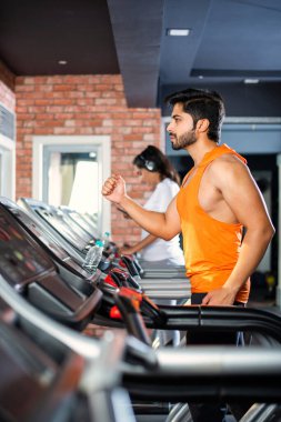 Hintli çekici çift fitness merkezinde ya da spor salonunda kardiyo eğitimi yapıyor, seçici odaklar - sağlık ve fitness konsepti