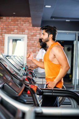 Hintli çekici çift fitness merkezinde ya da spor salonunda kardiyo eğitimi yapıyor, seçici odaklar - sağlık ve fitness konsepti