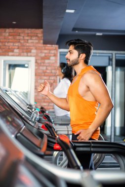 Hintli çekici çift fitness merkezinde ya da spor salonunda kardiyo eğitimi yapıyor, seçici odaklar - sağlık ve fitness konsepti