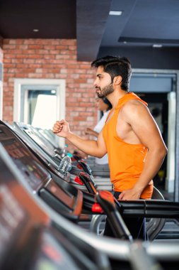 Hintli çekici çift fitness merkezinde ya da spor salonunda kardiyo eğitimi yapıyor, seçici odaklar - sağlık ve fitness konsepti