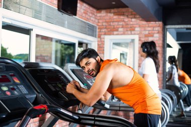 Hintli çekici çift fitness merkezinde ya da spor salonunda kardiyo eğitimi yapıyor, seçici odaklar - sağlık ve fitness konsepti