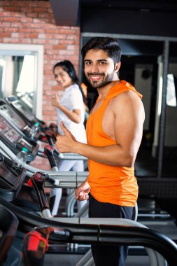 Hintli çekici çift fitness merkezinde ya da spor salonunda kardiyo eğitimi yapıyor, seçici odaklar - sağlık ve fitness konsepti