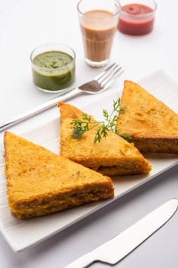 Sandviç ekmeği Pakora ya da Pakoda üçgeniyle servis edilen domates ketçapı, yeşil turşu, popüler Hint çay saati atıştırmalığı.