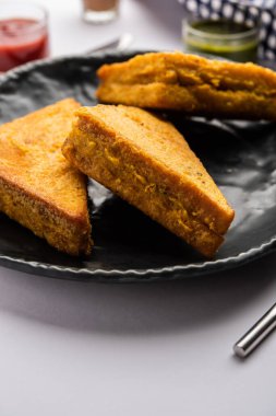 Sandviç ekmeği Pakora ya da Pakoda üçgeniyle servis edilen domates ketçapı, yeşil turşu, popüler Hint çay saati atıştırmalığı.