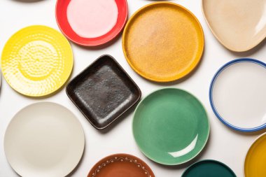 Beyaz arkaplan üzerinde grup halinde boş renkli seramik plakalar, üst görünüm