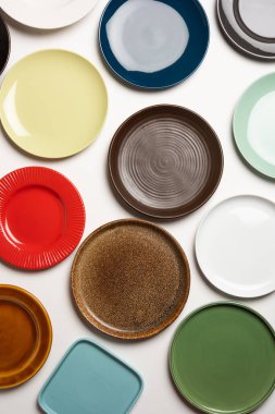 Beyaz arkaplan üzerinde grup halinde boş renkli seramik plakalar, üst görünüm