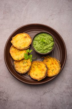 Lezzetli Brinjal Pakora veya çıtır patlıcanlı börek, Hint çay saati aperatifi yeşil baharatla servis edilir.