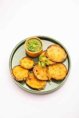 Lezzetli Brinjal Pakora veya çıtır patlıcanlı börek, Hint çay saati aperatifi yeşil baharatla servis edilir.