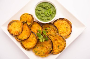 Lezzetli Brinjal Pakora veya çıtır patlıcanlı börek, Hint çay saati aperatifi yeşil baharatla servis edilir.