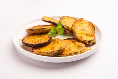 Lezzetli Brinjal Pakora veya çıtır patlıcanlı börek, Hint çay saati aperatifi yeşil baharatla servis edilir.