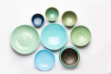 Boş renkli seramik kaselerin toplanması. Yukarıdan çekilen araç gereçleri grubu, üst görünüm, beyaz arkaplan üzerinde düz uzanır