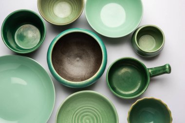 Boş renkli seramik kaselerin toplanması. Yukarıdan çekilen araç gereçleri grubu, üst görünüm, beyaz arkaplan üzerinde düz uzanır