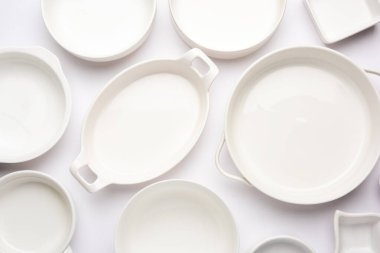 Boş renkli seramik kaselerin toplanması. Yukarıdan çekilen araç gereçleri grubu, üst görünüm, beyaz arkaplan üzerinde düz uzanır