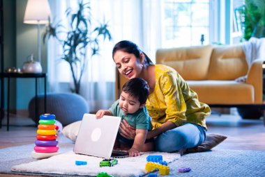 Sinirli Hintli bebek bilgisayarını kapatırken anne evde ofis işi yapıyor, dikkatini çekmeye çalışıyor, işi ve anneliği modern aile hayatında sevgi ve özenle dengeliyor.