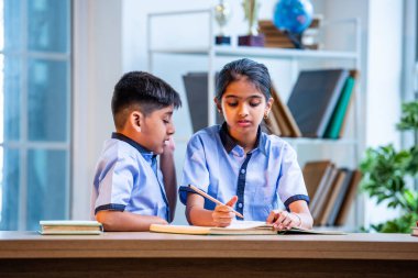 Okul üniformalarını giyerken arkadaşlarıyla dedikodu yapan, gizli konuşmalar yapan ve okuldaki çalışma saatleri arasında sessizce gülen Hintli okul çocukları.