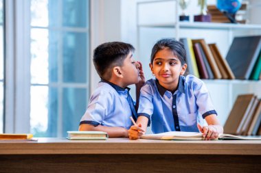 Okul üniformalarını giyerken arkadaşlarıyla dedikodu yapan, gizli konuşmalar yapan ve okuldaki çalışma saatleri arasında sessizce gülen Hintli okul çocukları.