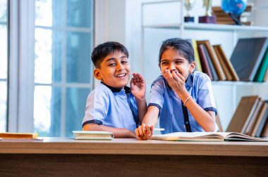 Okul üniformalarını giyerken arkadaşlarıyla dedikodu yapan, gizli konuşmalar yapan ve okuldaki çalışma saatleri arasında sessizce gülen Hintli okul çocukları.