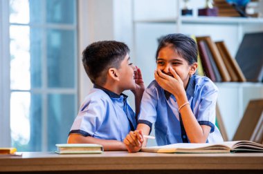 Okul üniformalarını giyerken arkadaşlarıyla dedikodu yapan, gizli konuşmalar yapan ve okuldaki çalışma saatleri arasında sessizce gülen Hintli okul çocukları.