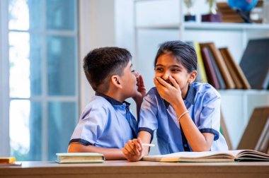 Okul üniformalarını giyerken arkadaşlarıyla dedikodu yapan, gizli konuşmalar yapan ve okuldaki çalışma saatleri arasında sessizce gülen Hintli okul çocukları.