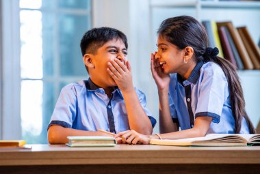 Okul üniformalarını giyerken arkadaşlarıyla dedikodu yapan, gizli konuşmalar yapan ve okuldaki çalışma saatleri arasında sessizce gülen Hintli okul çocukları.