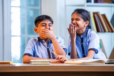 Okul üniformalarını giyerken arkadaşlarıyla dedikodu yapan, gizli konuşmalar yapan ve okuldaki çalışma saatleri arasında sessizce gülen Hintli okul çocukları.