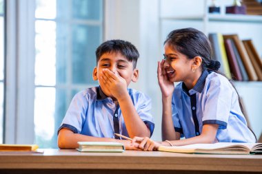 Okul üniformalarını giyerken arkadaşlarıyla dedikodu yapan, gizli konuşmalar yapan ve okuldaki çalışma saatleri arasında sessizce gülen Hintli okul çocukları.