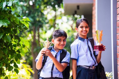 Hintli Okul Çocukları, Açık Hava Kameralarına Bakıyor Okul üniformaları Giyiyor, Başarı ve Başarı Kutlaması Mutlulukla poz verirken Güneşli bir günde gururla