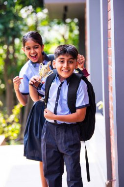 Hintli Okul Çocukları, Açık Hava Kameralarına Bakıyor Okul üniformaları Giyiyor, Başarı ve Başarı Kutlaması Mutlulukla poz verirken Güneşli bir günde gururla