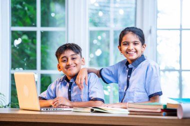 Sınıf Üniformalarını Giyerken Dizüstü Bilgisayarda Birlikte Çalışan Hintli Okul Çocukları, Grup Öğrenimi, Bilgi Paylaşımı, Eğitim sırasında Akademik Görevler Kullanımı Teknolojisi İşbirliği