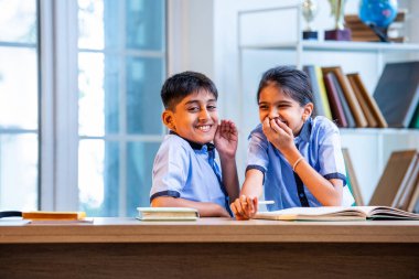 Okul üniformalarını giyerken arkadaşlarıyla dedikodu yapan, gizli konuşmalar yapan ve okuldaki çalışma saatleri arasında sessizce gülen Hintli okul çocukları.