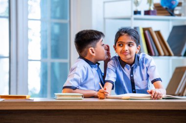 Okul üniformalarını giyerken arkadaşlarıyla dedikodu yapan, gizli konuşmalar yapan ve okuldaki çalışma saatleri arasında sessizce gülen Hintli okul çocukları.