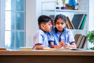 Okul üniformalarını giyerken arkadaşlarıyla dedikodu yapan, gizli konuşmalar yapan ve okuldaki çalışma saatleri arasında sessizce gülen Hintli okul çocukları.