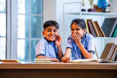 Okul üniformalarını giyerken arkadaşlarıyla dedikodu yapan, gizli konuşmalar yapan ve okuldaki çalışma saatleri arasında sessizce gülen Hintli okul çocukları.