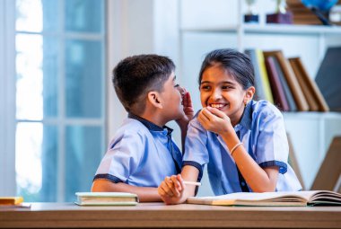 Okul üniformalarını giyerken arkadaşlarıyla dedikodu yapan, gizli konuşmalar yapan ve okuldaki çalışma saatleri arasında sessizce gülen Hintli okul çocukları.
