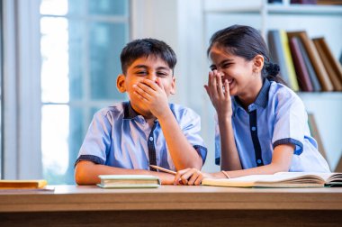 Okul üniformalarını giyerken arkadaşlarıyla dedikodu yapan, gizli konuşmalar yapan ve okuldaki çalışma saatleri arasında sessizce gülen Hintli okul çocukları.