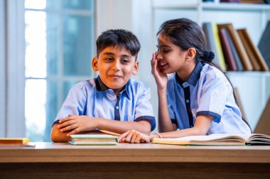 Okul üniformalarını giyerken arkadaşlarıyla dedikodu yapan, gizli konuşmalar yapan ve okuldaki çalışma saatleri arasında sessizce gülen Hintli okul çocukları.