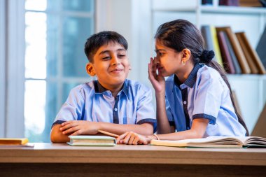 Okul üniformalarını giyerken arkadaşlarıyla dedikodu yapan, gizli konuşmalar yapan ve okuldaki çalışma saatleri arasında sessizce gülen Hintli okul çocukları.