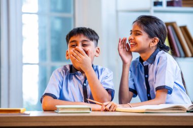 Okul üniformalarını giyerken arkadaşlarıyla dedikodu yapan, gizli konuşmalar yapan ve okuldaki çalışma saatleri arasında sessizce gülen Hintli okul çocukları.