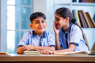 Okul üniformalarını giyerken arkadaşlarıyla dedikodu yapan, gizli konuşmalar yapan ve okuldaki çalışma saatleri arasında sessizce gülen Hintli okul çocukları.