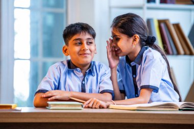 Okul üniformalarını giyerken arkadaşlarıyla dedikodu yapan, gizli konuşmalar yapan ve okuldaki çalışma saatleri arasında sessizce gülen Hintli okul çocukları.