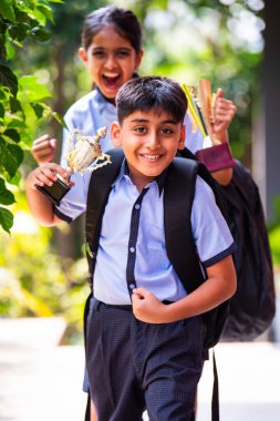 Hintli Okul Çocukları, Açık Hava Kameralarına Bakıyor Okul üniformaları Giyiyor, Başarı ve Başarı Kutlaması Mutlulukla poz verirken Güneşli bir günde gururla