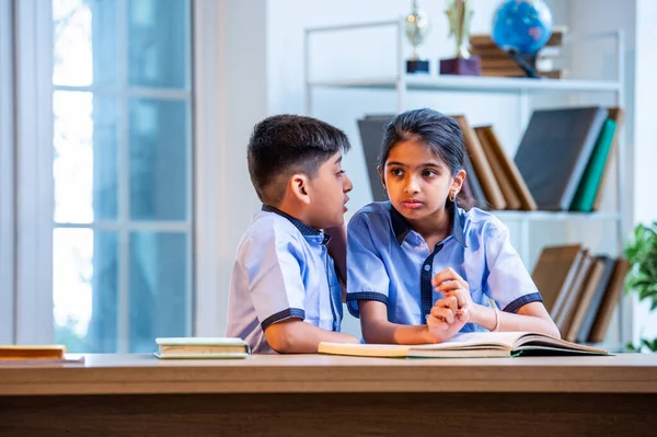 Okul üniformalarını giyerken arkadaşlarıyla dedikodu yapan, gizli konuşmalar yapan ve okuldaki çalışma saatleri arasında sessizce gülen Hintli okul çocukları.