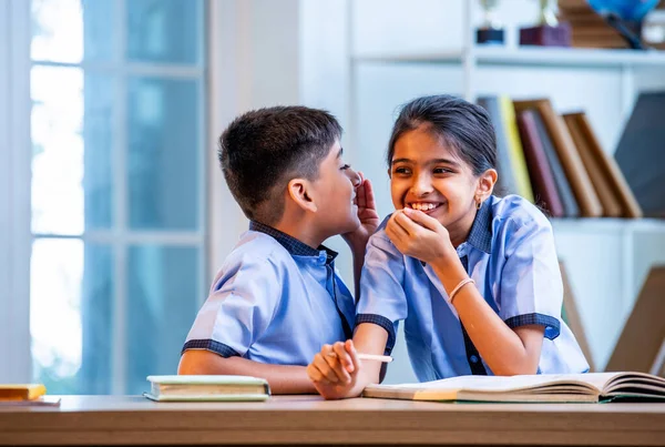 Okul üniformalarını giyerken arkadaşlarıyla dedikodu yapan, gizli konuşmalar yapan ve okuldaki çalışma saatleri arasında sessizce gülen Hintli okul çocukları.