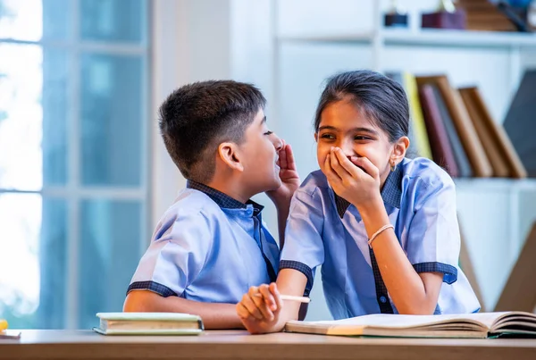 Okul üniformalarını giyerken arkadaşlarıyla dedikodu yapan, gizli konuşmalar yapan ve okuldaki çalışma saatleri arasında sessizce gülen Hintli okul çocukları.