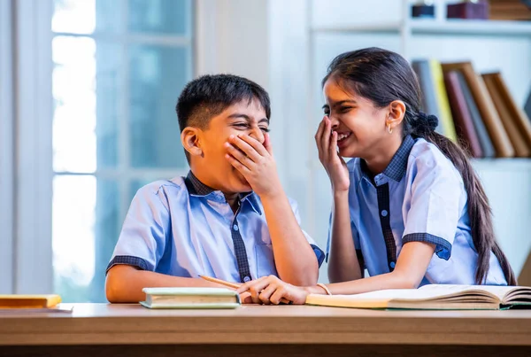 Okul üniformalarını giyerken arkadaşlarıyla dedikodu yapan, gizli konuşmalar yapan ve okuldaki çalışma saatleri arasında sessizce gülen Hintli okul çocukları.