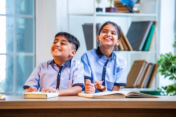 Hintli okul çocukları okul üniformalarını giyerken yüksek sesle gülüyorlar, birlikte neşeli bir anın tadını çıkarıyorlar, akademik tatilde kahkahalarla neşe ve bağ kuruyorlar.