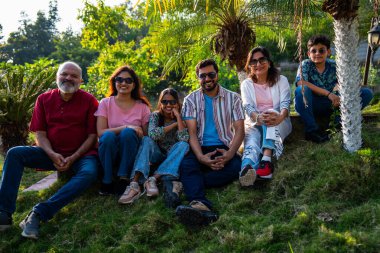 Hint ailesi çimlerin yamacında oturmuş mutlu anların tadını çıkarıyor ve gevşemiş sohbetler ediyorlar. Büyükbabalar, ebeveynler ve çocuklar doğada huzur içinde vakit geçiriyorlar. Birbirlerine bağlanıp gülümsüyorlar.