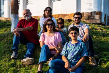 Hint ailesi çimlerin yamacında oturmuş mutlu anların tadını çıkarıyor ve gevşemiş sohbetler ediyorlar. Büyükbabalar, ebeveynler ve çocuklar doğada huzur içinde vakit geçiriyorlar. Birbirlerine bağlanıp gülümsüyorlar.