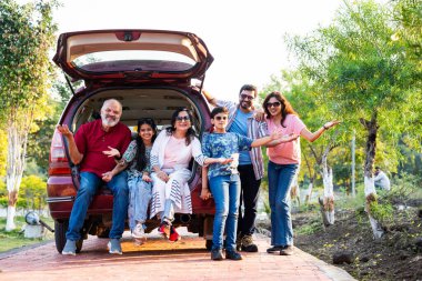 Hintli aile dışarıda arabada oturup pikniğe gitmeye hazırlar. Eğlenceli anların tadını çıkarırlar. Büyükbabalar, ebeveynler ve çocuklar birlikte dinlenirler.